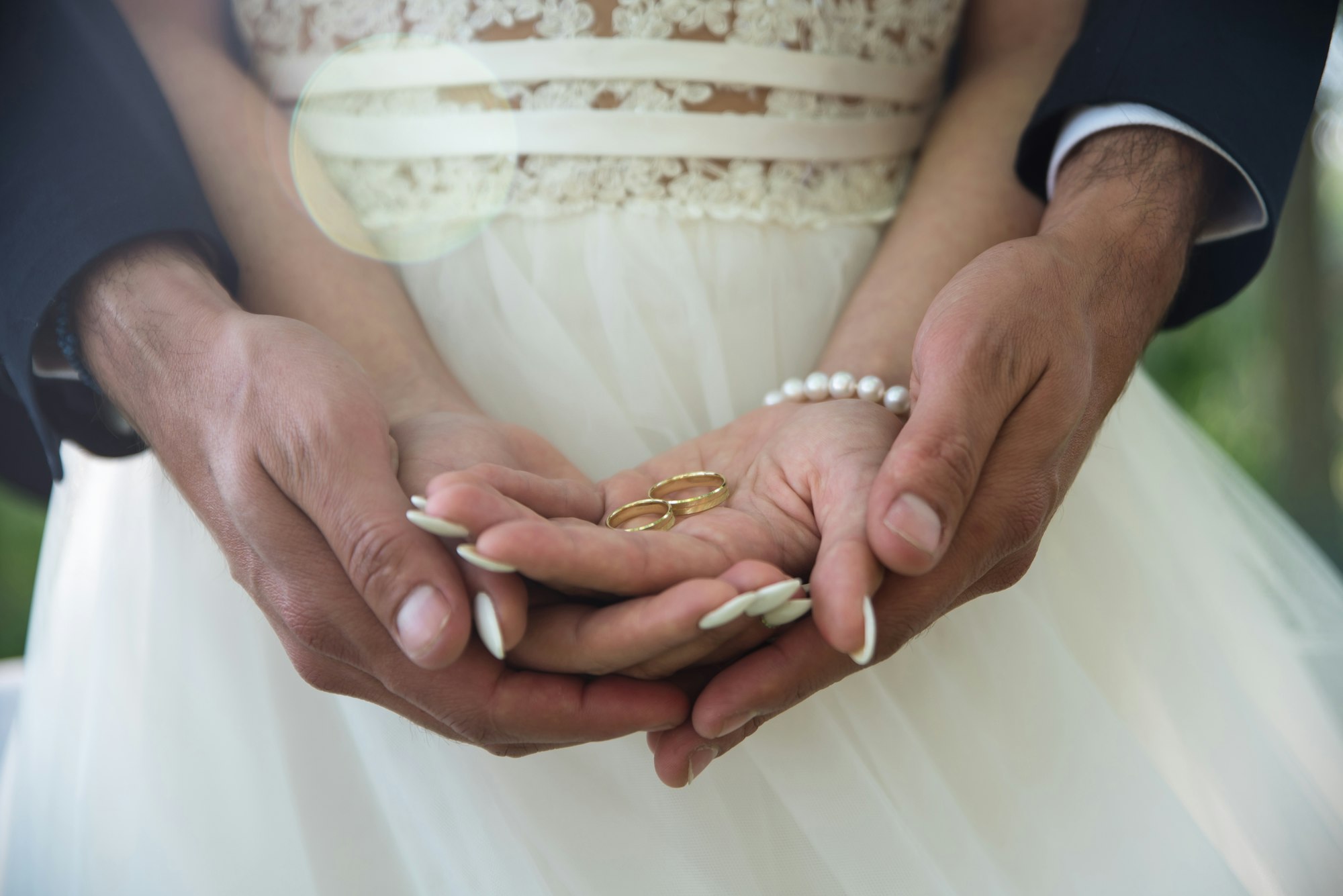 Pareja agarrando anillos de boda, Consejos para tu itinerario ideal de viajes de novios, Qbodas y viajes, organización de viajes de novios.
